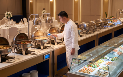 Buffet de banquete de hotel chileno con data logger de temperatura monitoreando mesas calientes y frías durante evento para cumplimiento del DS 977 MINSAL