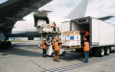 Transferencia de carga de cadena de frío entre avión y camión refrigerado en terminal aérea chilena con data logger Tempmate documentando condiciones de temperatura